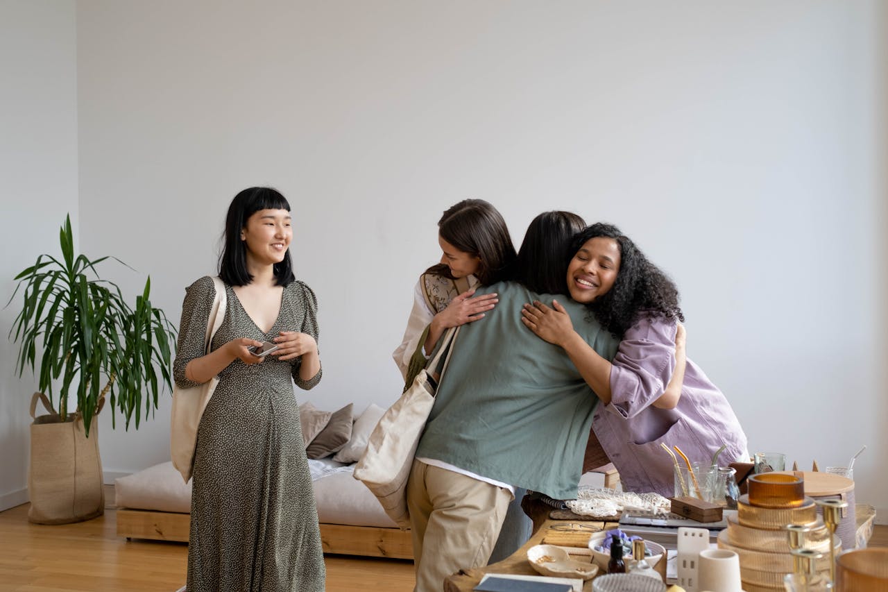 A group of diverse women sharing a hug and conversation in a cozy indoor setting.